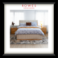 A bedroom scene featuring a large, plush bed with a fabric bedhead and foot, bedsides and a large rug. The Rowes Furniture logo features.