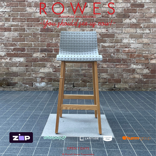 Bar stool with woven seat against a brick wall, featuring the brand 'Rowes'.