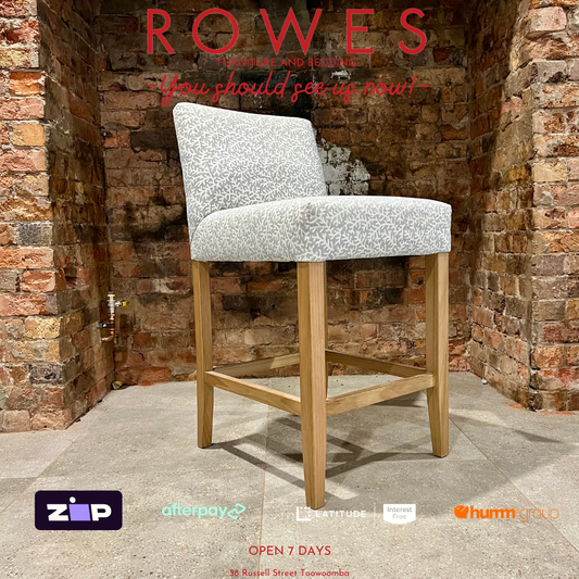 Chair with gray cushioned seat and wooden legs against a brick wall, featuring the brand 'Rowes'.