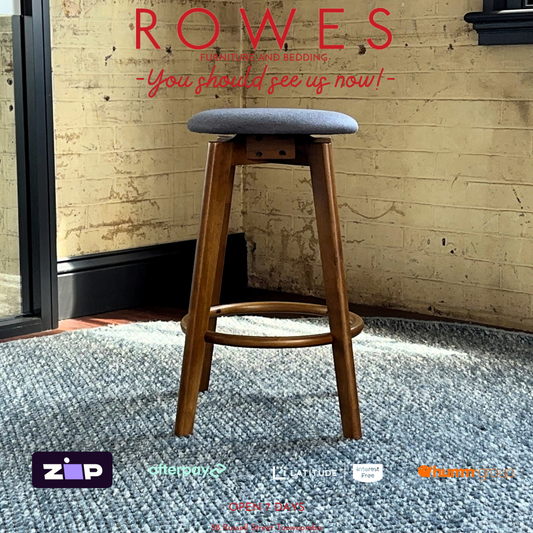 Wooden bar stool with gray cushioned seat on a blue rug, with 'Rowes' branding above.