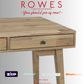 Wooden desk with 'Rowes Furniture and Bedding' text and logos on a light gray background