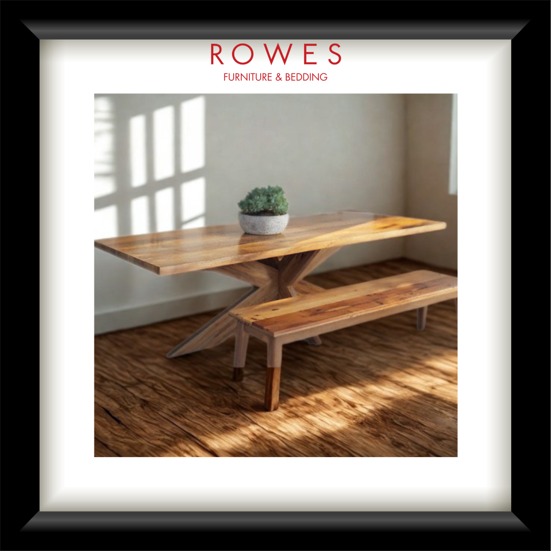 Wooden dining table with bench in a room with sunlight streaming through a window, branded 'Rowes Furniture & Bedding'.