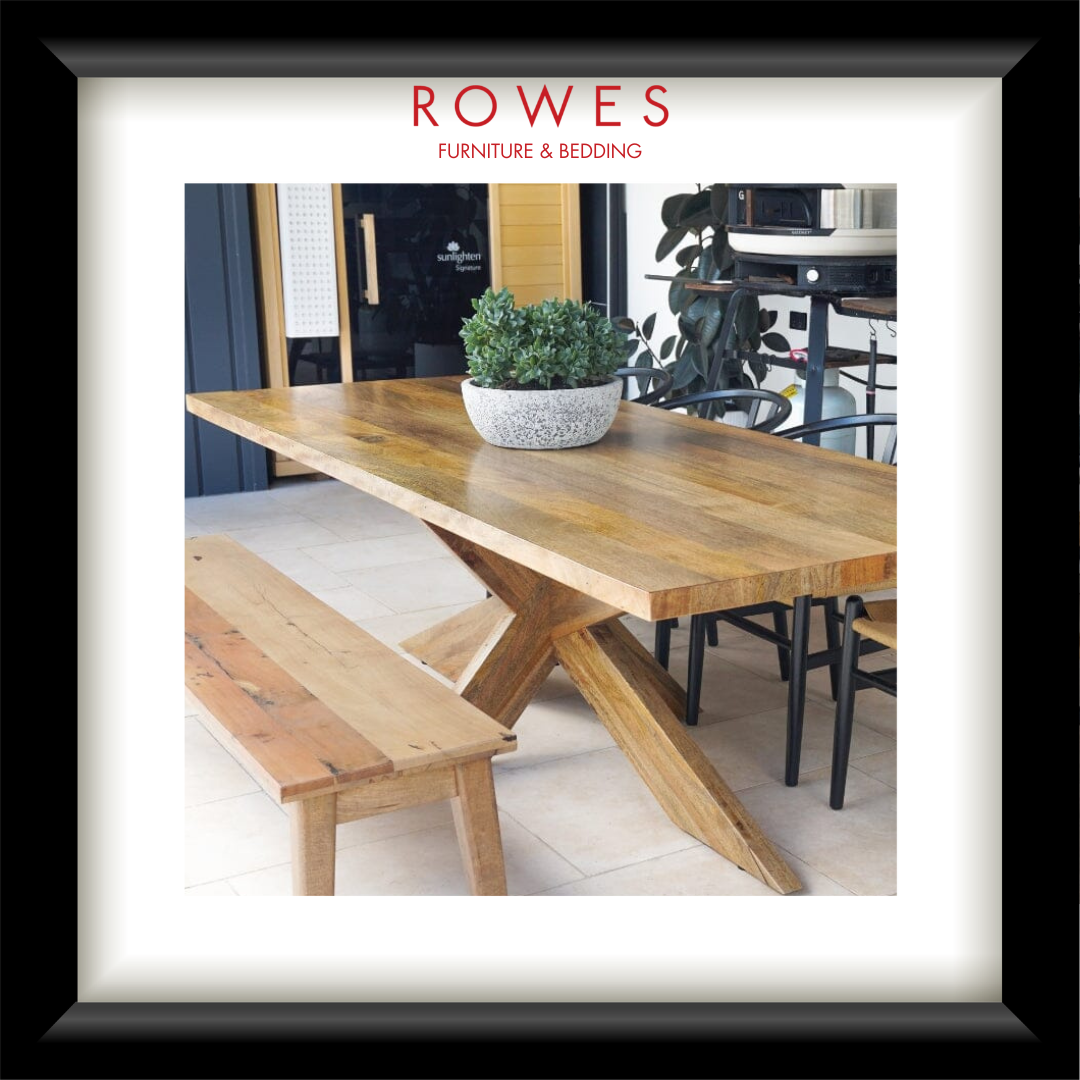 Wooden dining table with bench and potted plant in a room setting, featuring 'Rowes Furniture & Bedding' logo.