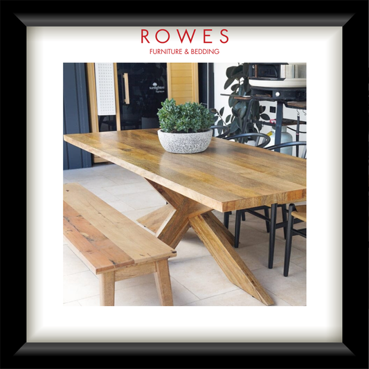 Wooden dining table with bench and potted plant in a room setting, featuring 'Rowes Furniture & Bedding' logo.