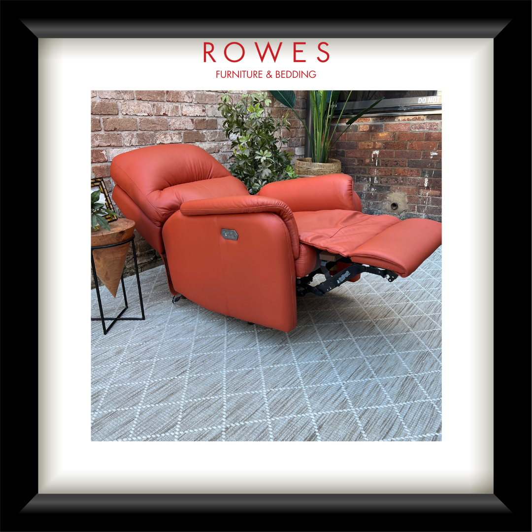 Red recliner chair in a room with plants and a brick wall, branded 'Rowes Furniture & Bedding'.