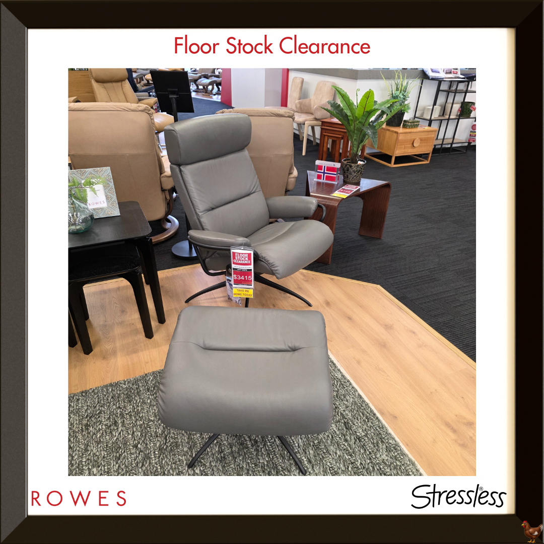 Gray recliner chair with ottoman in a showroom setting, featuring 'Rowes' and 'Stressless' branding.