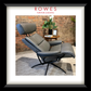 Gray recliner chair with headrest in a room with a brick wall and plants.