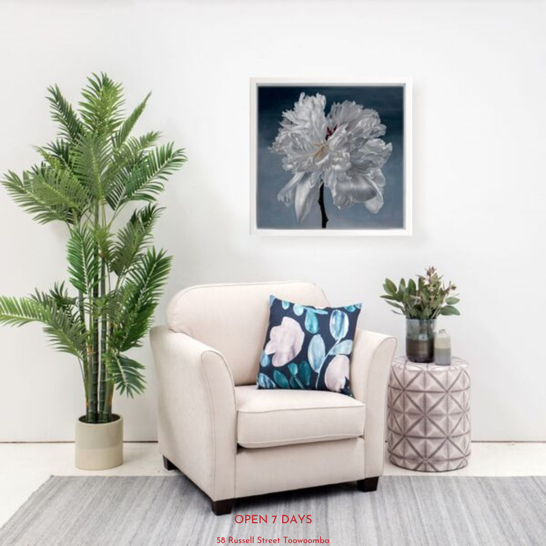 Living room with a white armchair, decorative pillow, and potted plants.