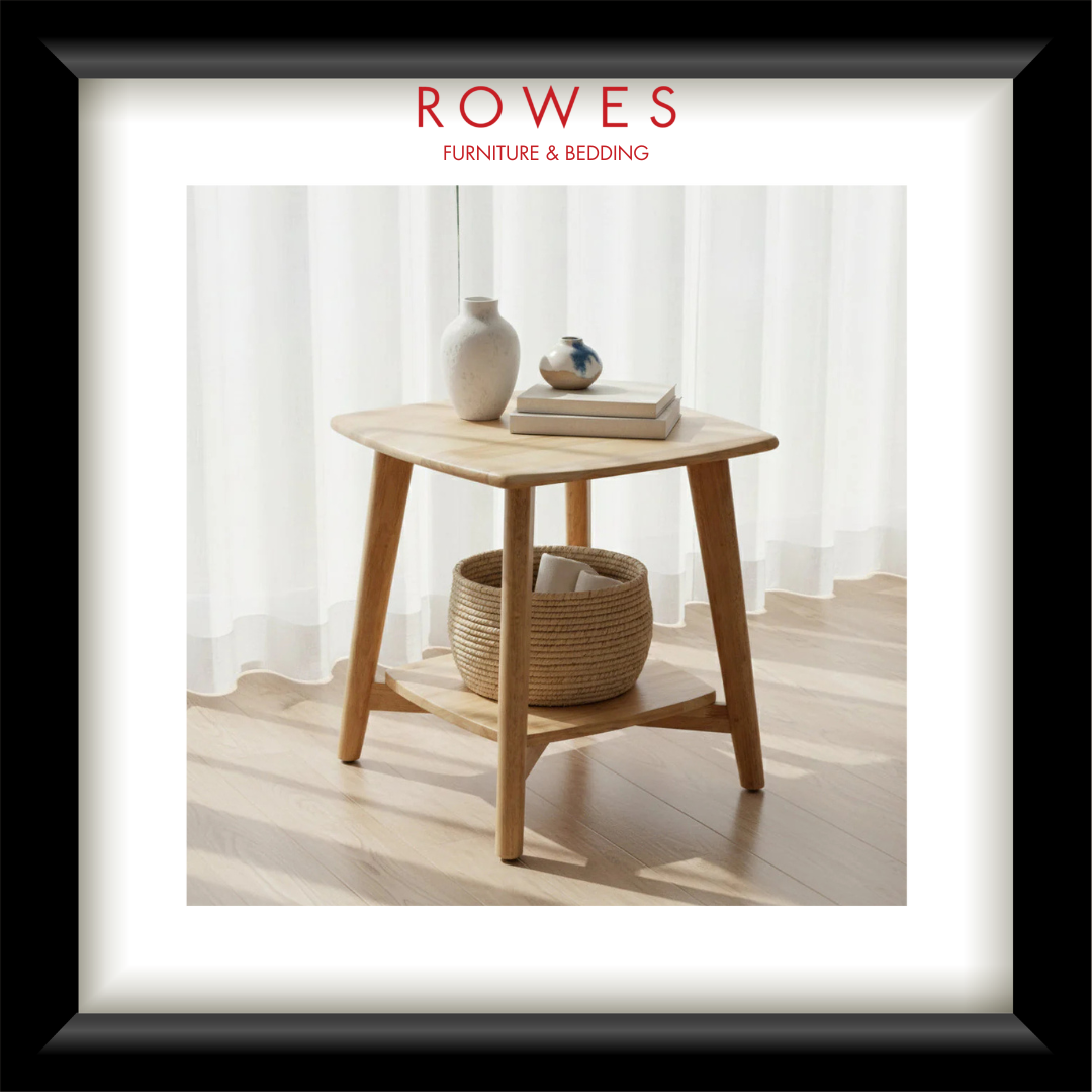 Wooden side table with decor items in a room with white curtains, featuring 'Rowes Furniture & Bedding' logo.