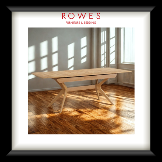 Wooden dining table in a room with large windows, featuring the Rowes Furniture & Bedding logo.