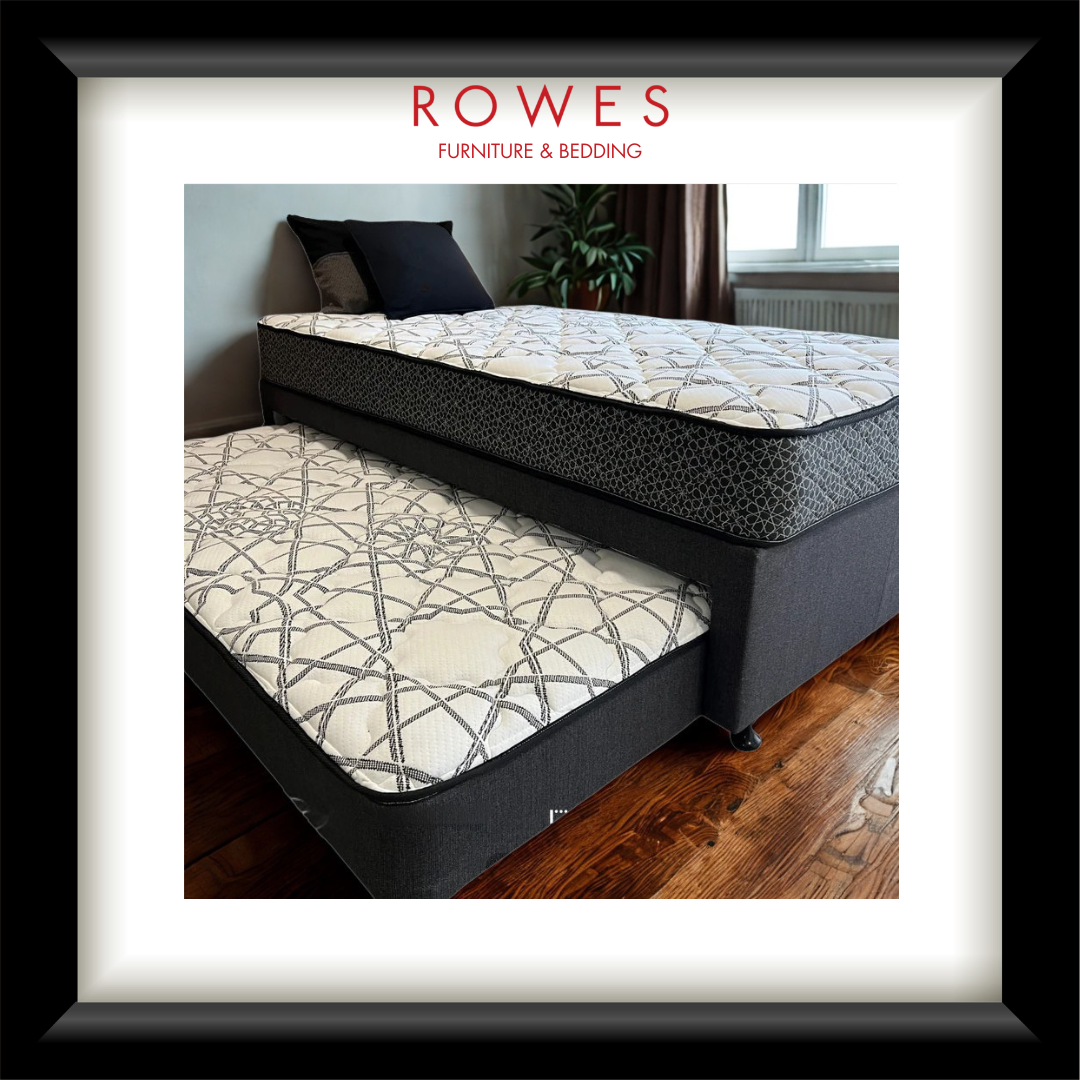 Gray upholstered bed with patterned mattress in a room setting, featuring 'Rowes Furniture & Bedding' logo.