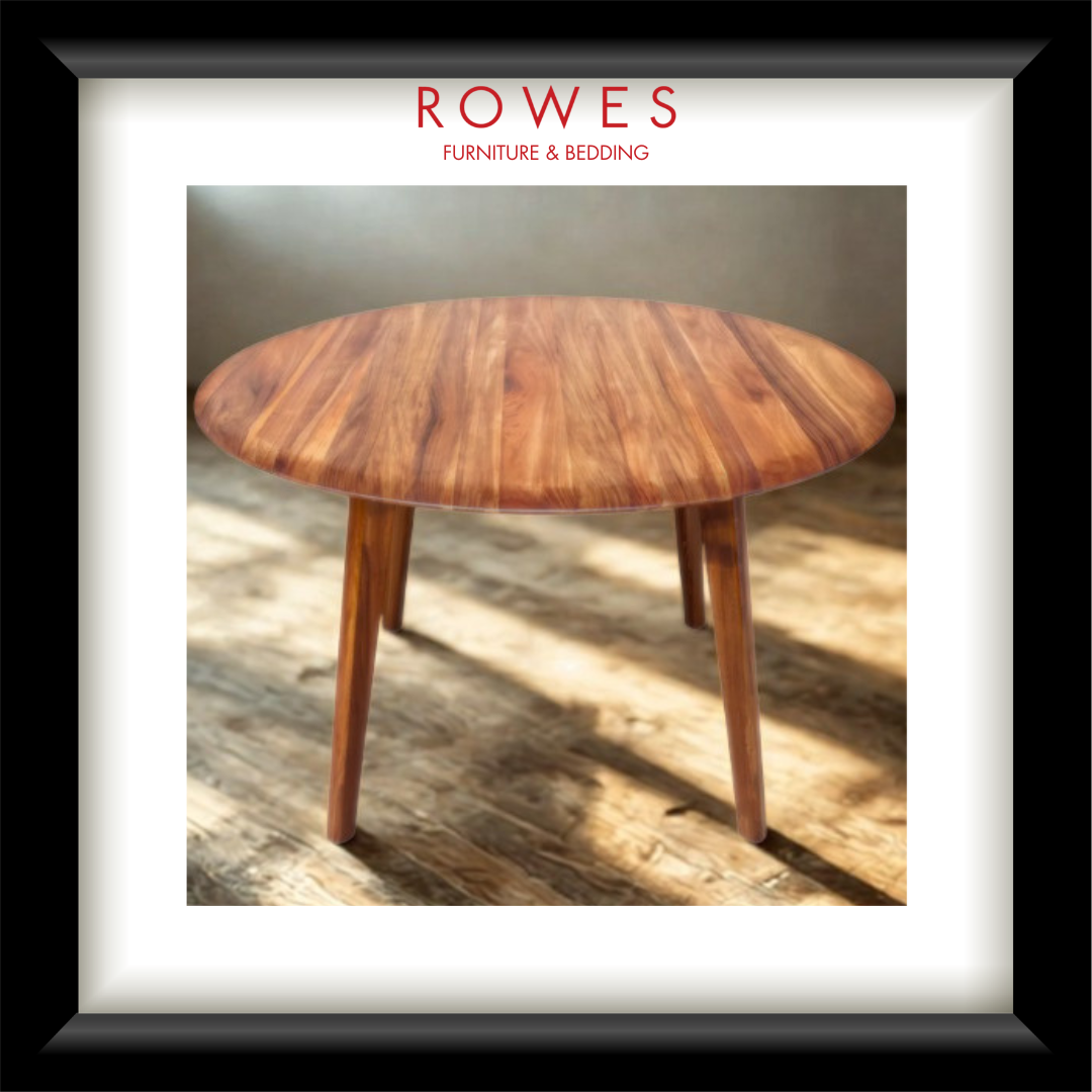 A framed product image of a round wooden dining table with a warm medium-brown wood grain finish and tapered legs, presented in a black frame with a white mat. The brand name 'ROWES FURNITURE & BEDDING' is printed in red at the top of the image.